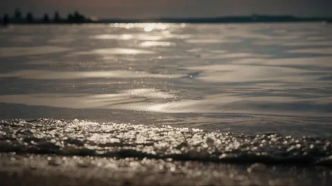 Soft waves gently lapping on a sandy beach at sunset. Slow motion video Video stock 286121813