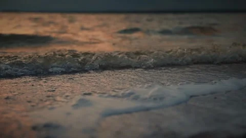 Soft waves gently lapping on a sandy beach at sunset. Slow motion video Video stock 286122132