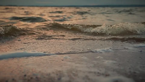 Soft waves gently lapping on a sandy beach at sunset. Slow motion video Video stock 286122177
