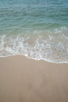 Soft waves gently touch sandy shore Stock Photos