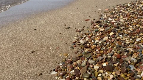 Soft waves of the Mediterranean Sea roll onto a sandy beach, wet pebbles glisten Stock Footage 301407202