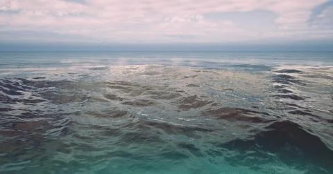 Soft waves rolling gently under a pastel sky at a tranquil ocean Illustrazione stock