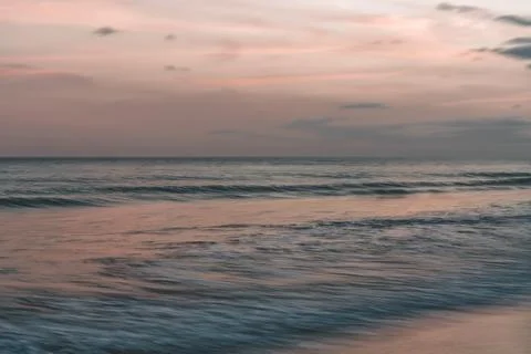 Soft waves rolling in under a pastel-colored sky at dusk, abstract Stock Photos