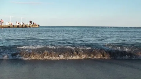 Soft waves on a sandy beach. Breakwater with walking people Stock Footage 77338794