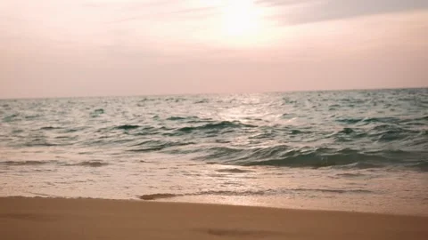 Soft waves wash over the sandy shore as the sunset, creating a serene and Stock Footage 317190631