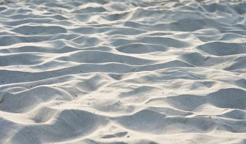 Soft white beach sand texture with natural ripples in warm evening light Fotos Stock