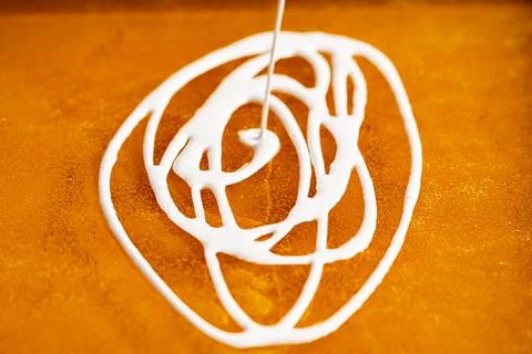 Soft white caramel flows forming a pattern on the yellow caramel mass. Cooking 스톡 사진