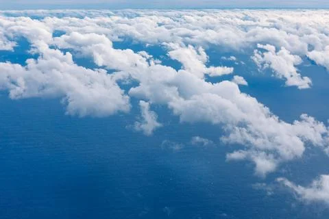 Soft white clouds drift above a vast blue ocean Fotos Stock