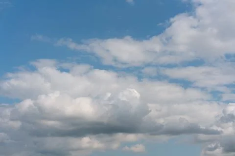 Soft white clouds drift across a clear blue sky Stock Photos