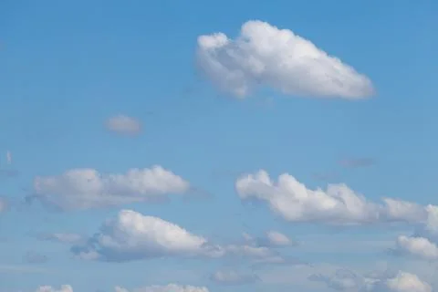 Soft white clouds drift across clear blue sky Stock Photos