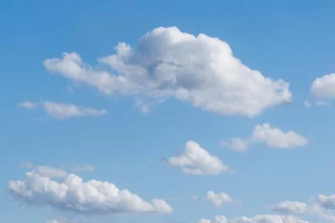 Soft white clouds drift across a bright blue sky Stock Photos