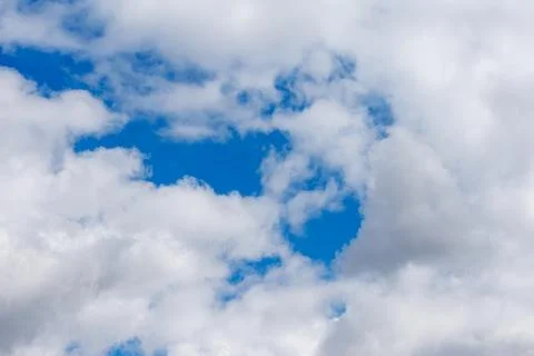 Soft white clouds drift against a vibrant blue sky Stock Photos