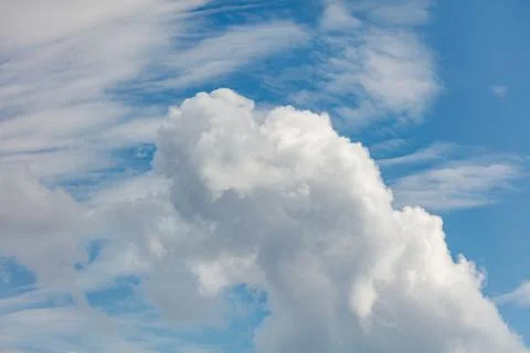 Soft white clouds drift against a bright blue sky Stock Photos