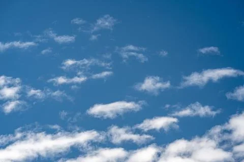 Soft white clouds drifting across a clear blue sky with natural copy space Stock Photos