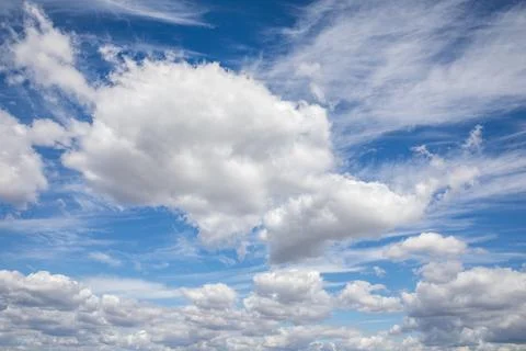 Soft white clouds float across a clear blue sky, creating a serene atmosphe.. Stockfoto's