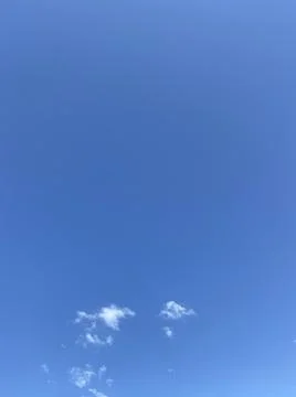 Soft white clouds floating on a bright blue summer sky Stock Photos
