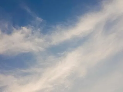 Soft white clouds stretching across a blue sky with gentle gradients Stock Photos