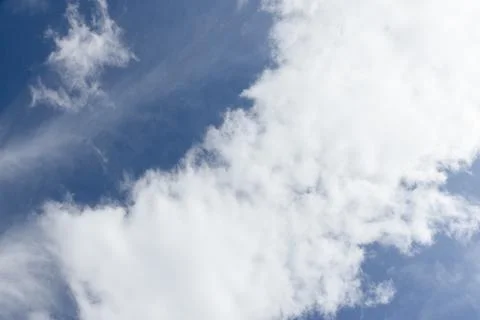 Soft white cumulus and wispy cirrus clouds drift across a vibrant blue sky Stock Photos