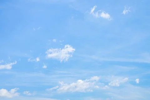 Soft white cumulus clouds spread through a bright blue sky, giving a beauti.. Stock Photos