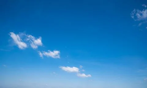 Soft white cumulus clouds spread through a bright blue sky, giving a beauti.. Stock Photos
