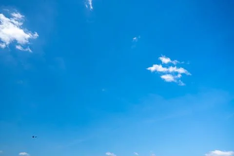 Soft white cumulus clouds spread through a bright blue sky, giving a beauti.. Stock Photos