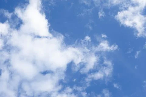 Soft white cumulus clouds spreading across a vibrant blue sky on a bright s.. Photos