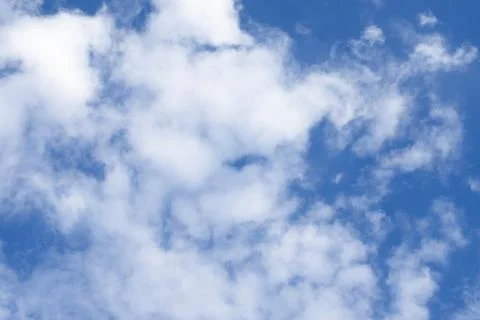 Soft white cumulus clouds spreading across a vibrant blue sky on a bright s.. Photos