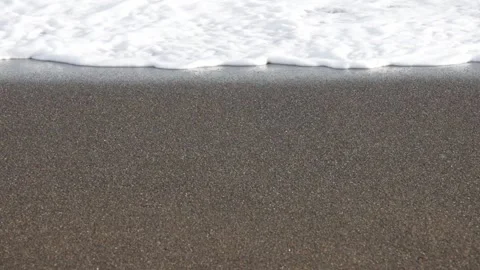 Soft white frothy wave flowing onto flat clean sandy beach Stock Footage 303256496