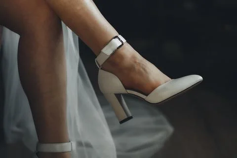 Soft white heels rest on a bare foot Foto stock