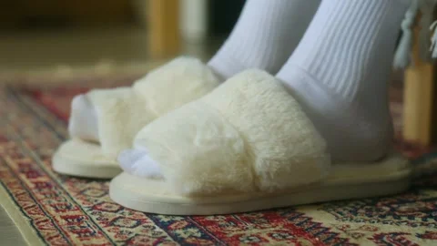 Soft white slippers wait on plush carpet. Woman in warm white socks puts them on Video stock 312846268