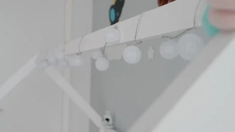 Soft white string lights hanging on indoor wooden frame in minimal room Stock Footage 314272974