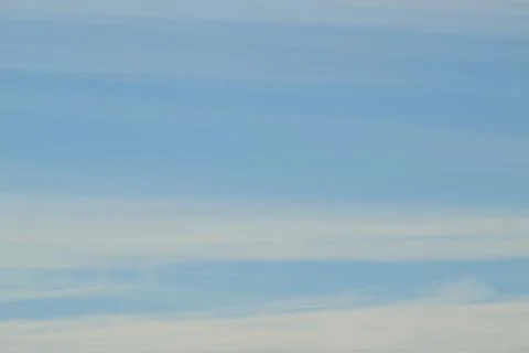 Soft white wispy clouds on a clear blue sky background. Stock Photos