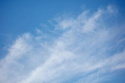 Soft wispy clouds drift across a clear blue sky Foto stock
