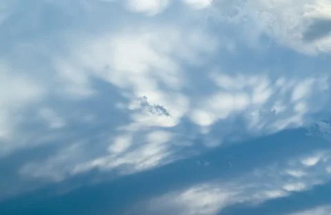 Soft, wispy stratocumulus clouds spread across a pale blue sky, with gentle Stock Photos
