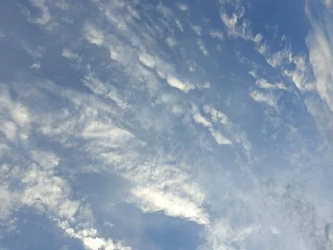 Soft wispy white cirrus clouds scattered across a deep blue sky creates a pea Stock Photos