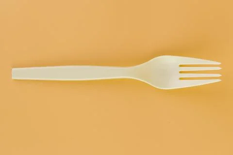 Soft yellow background pair of plastic white forks disposable tableware eco Stock Photos