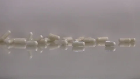 A softgel capsules falling on reflective surface, slow motion 库存影片 88742622