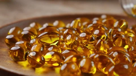 Softgel capsules pouring out of opened glass bottle Видео 330924942