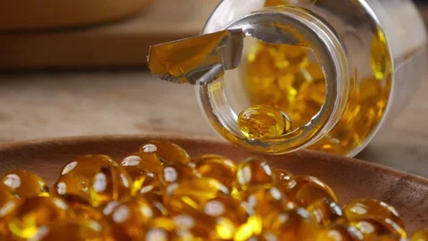 Softgel capsules pouring out of opened glass bottle Vídeos de archivo 330924944