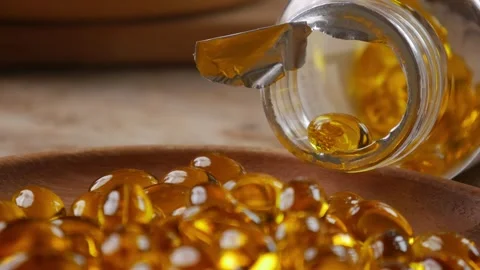 Softgel capsules pouring out of opened glass bottle Vidéo 331056087