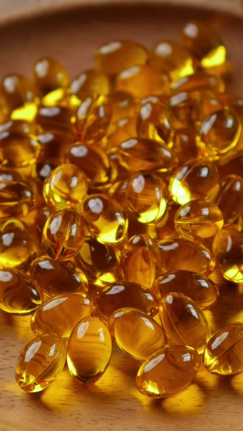 Softgel capsules pouring out of opened glass bottle Stockbeeldmateriaal 331056092