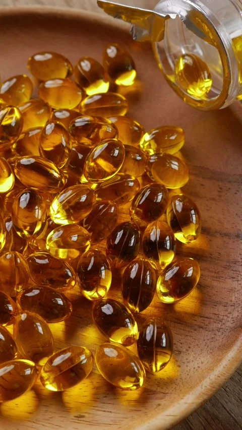 Softgel capsules pouring out of opened glass bottle Video stock 331115397