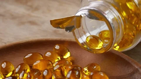 Softgel capsules pouring out of opened glass bottle Video stock 331900978