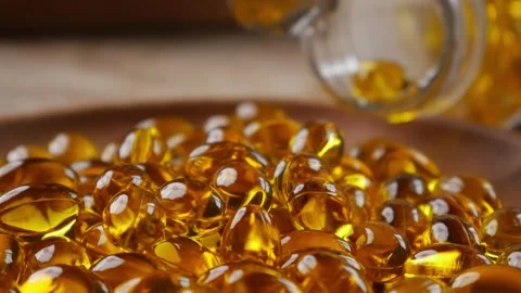Softgel capsules pouring out of opened glass bottle Stock Footage 332920642