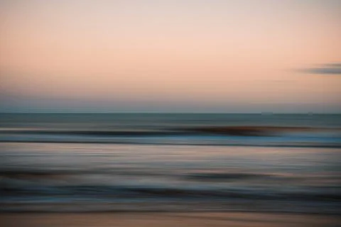 Softly blurred ocean waves under a peach and blue evening sky. Stock-Fotos