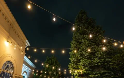 Softly Glowing String Lights Cast Atmosphere Ideal For Outdoor Festivities And Stock Photos