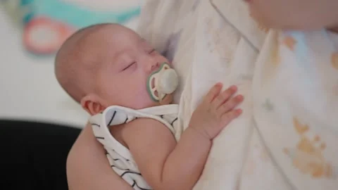 Softly sleeping infant rests in parent's arms Stock Footage 340312470