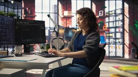 Software developer at agency office coding on her computer, Foto stock