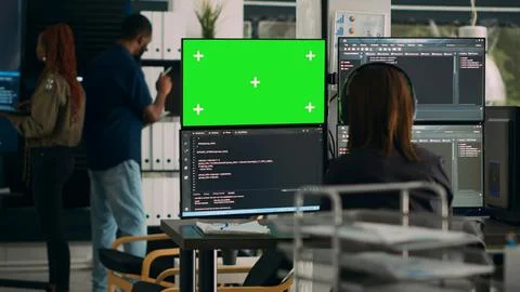 Software developer analyzing greenscreen and server code on multiple monitors Stockfoto's