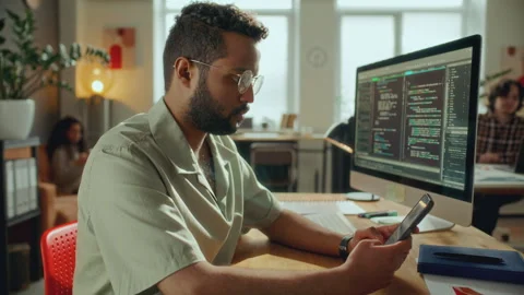Software Developer Checking Smartphone at Desk in Modern Office Stock Footage 305312882